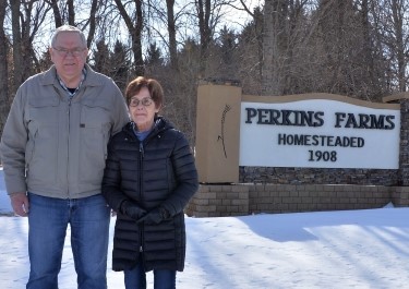 Bryan and Sharon Perkins standing in front of Perkins Farms Homesteaded sign.