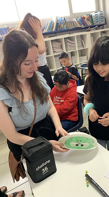 A Lakeland College student looks over a young student's art project in Ensenada Mexico