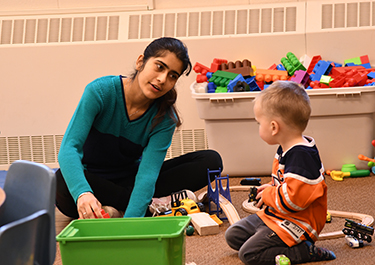  A child in the preschool room poses with a student.